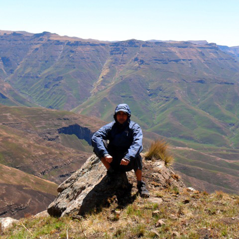 Person sitting on rock with mountain view.