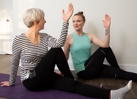 Two women practicing yoga and high-fiving.