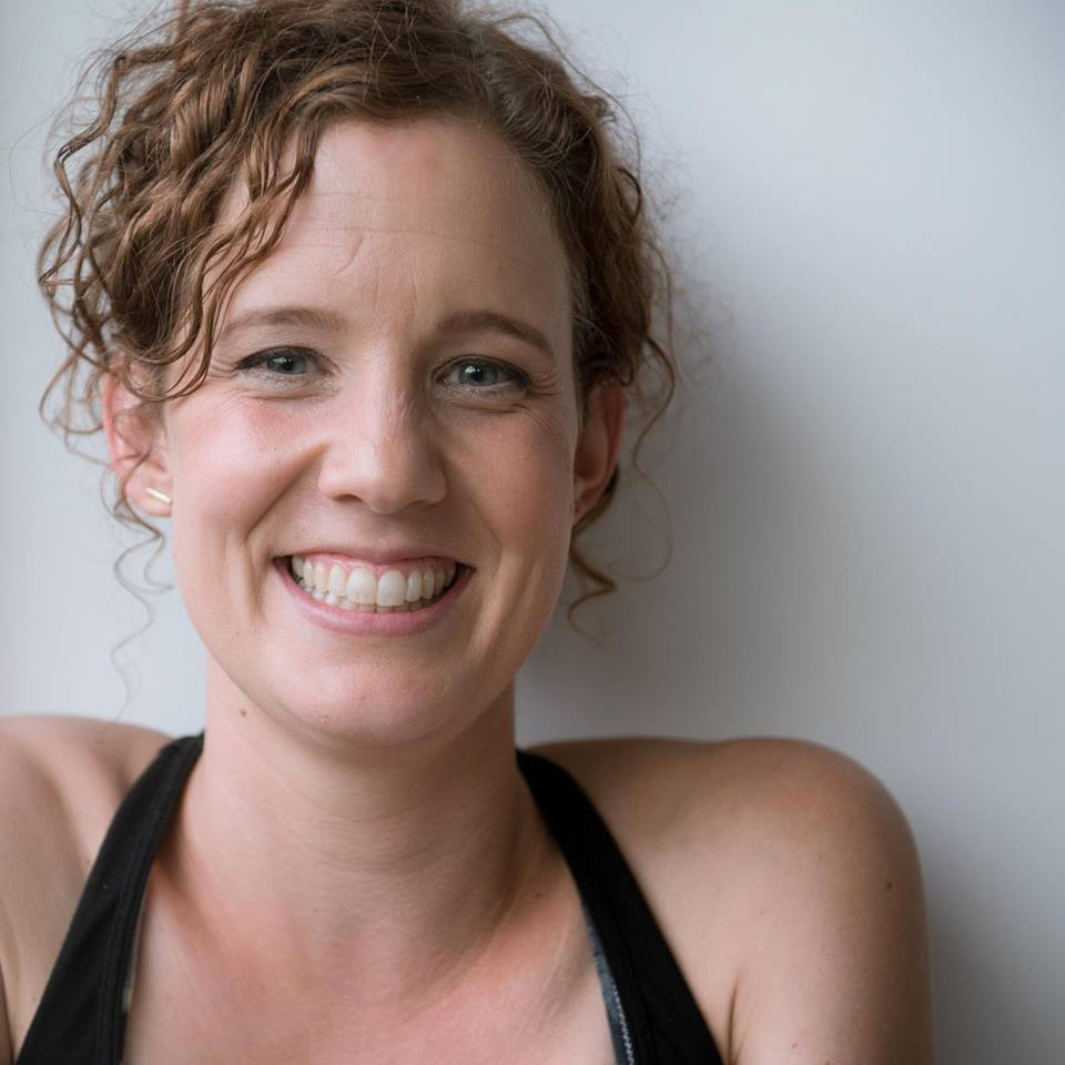 Smiling woman with curly hair, wearing black.