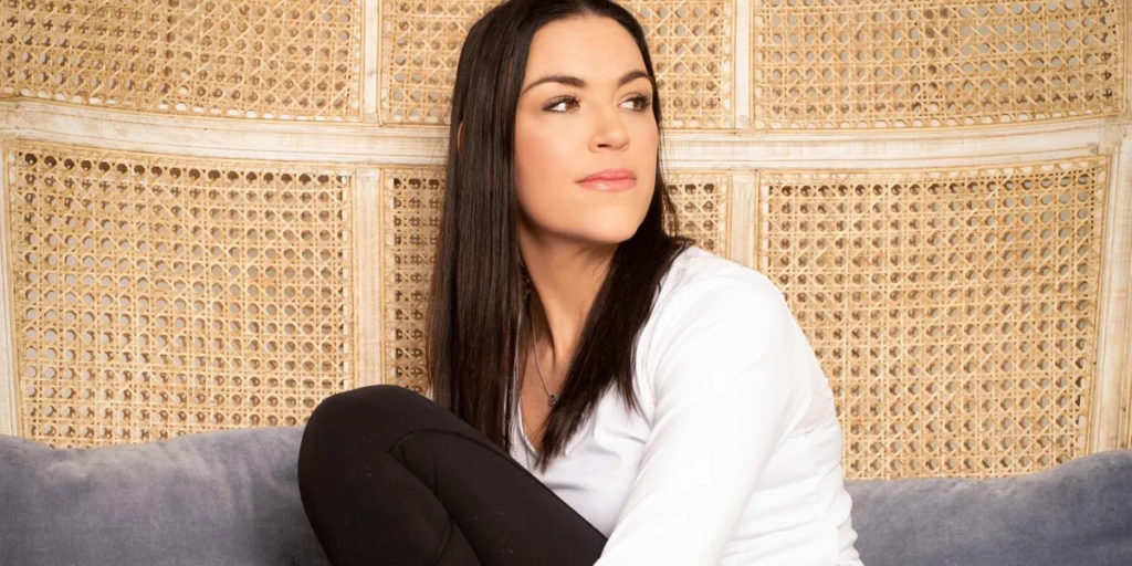 Woman sitting on couch with woven backdrop.