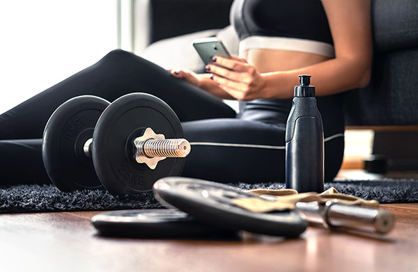 Person sitting near dumbbells and water bottle.