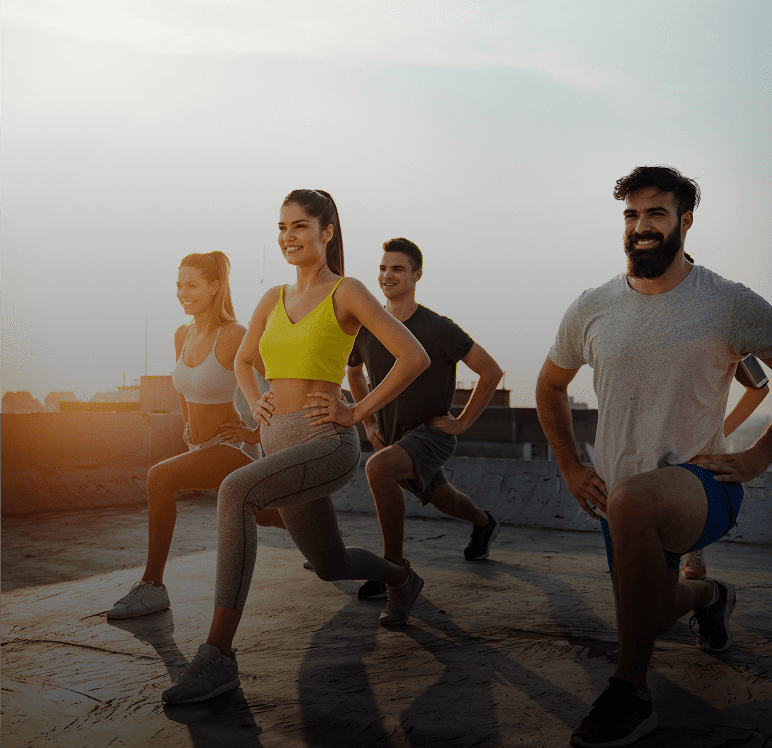 Group exercising on rooftop at sunrise